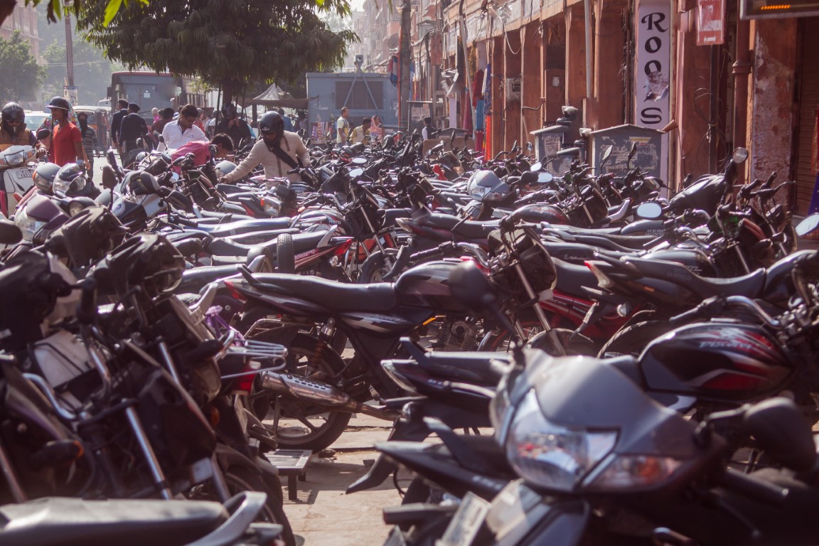 JAIPUR, INDIA, 2.12.2016: Huge amount of motorbikes and scooters parked on a street in Jaipur. People walking past. Motorcycle parking.
